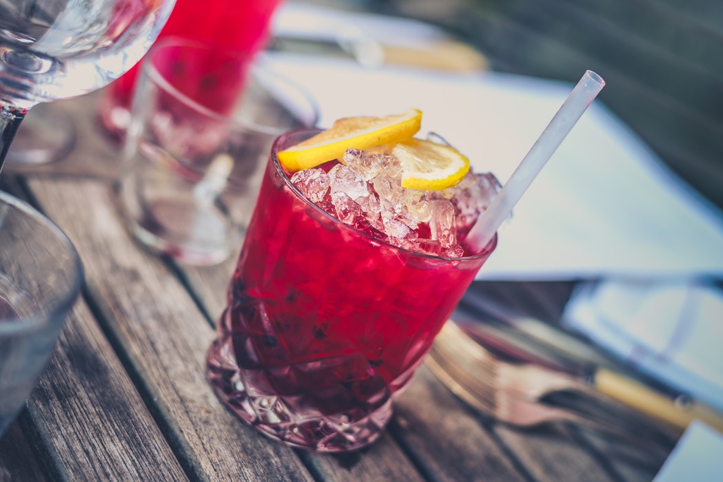 A pink cocktail with ice and lemon